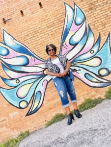 Melanie posing in front of painted butterfly wings